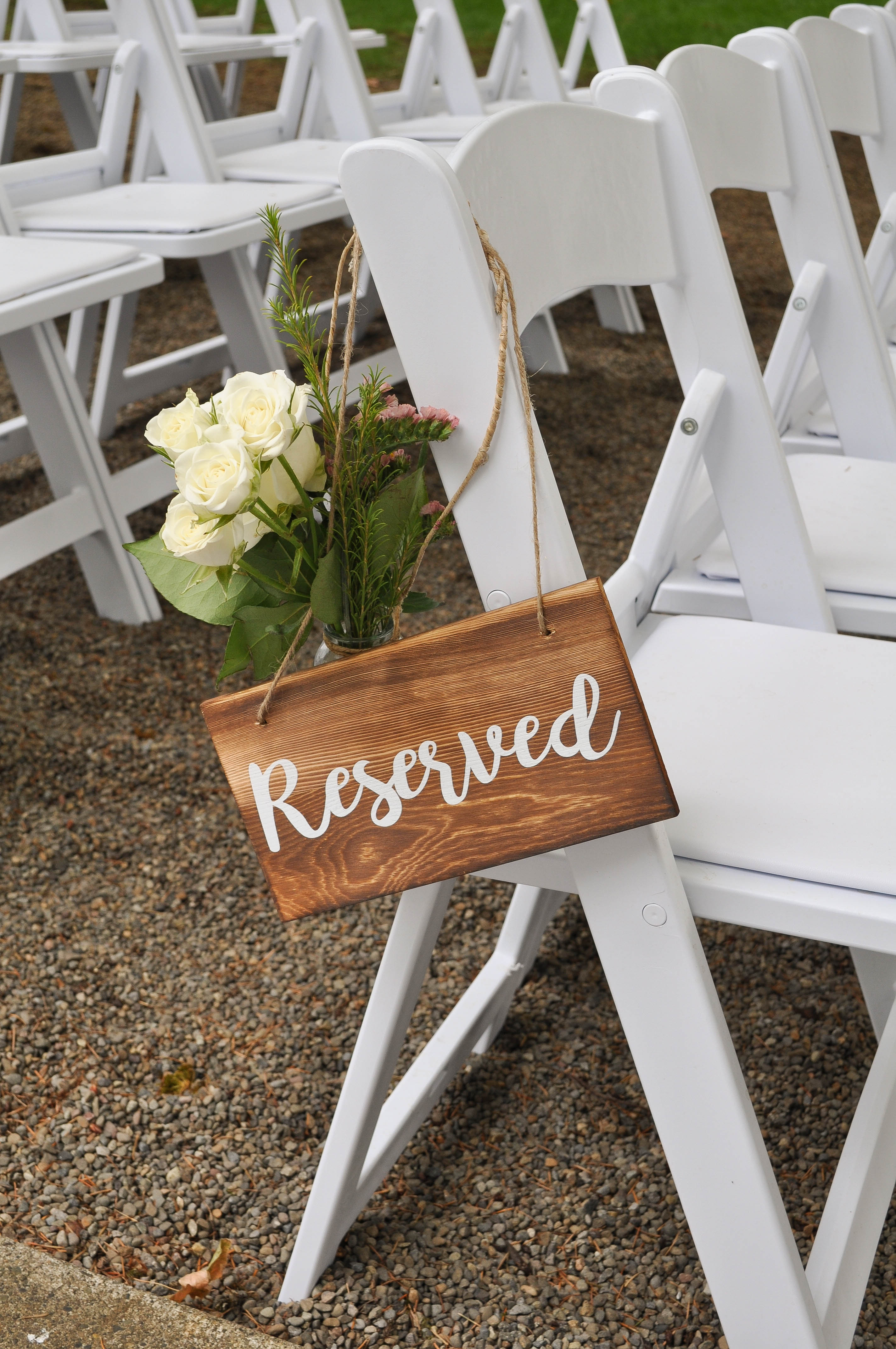 Reserved sign with white roses and greenery on ceremony chair